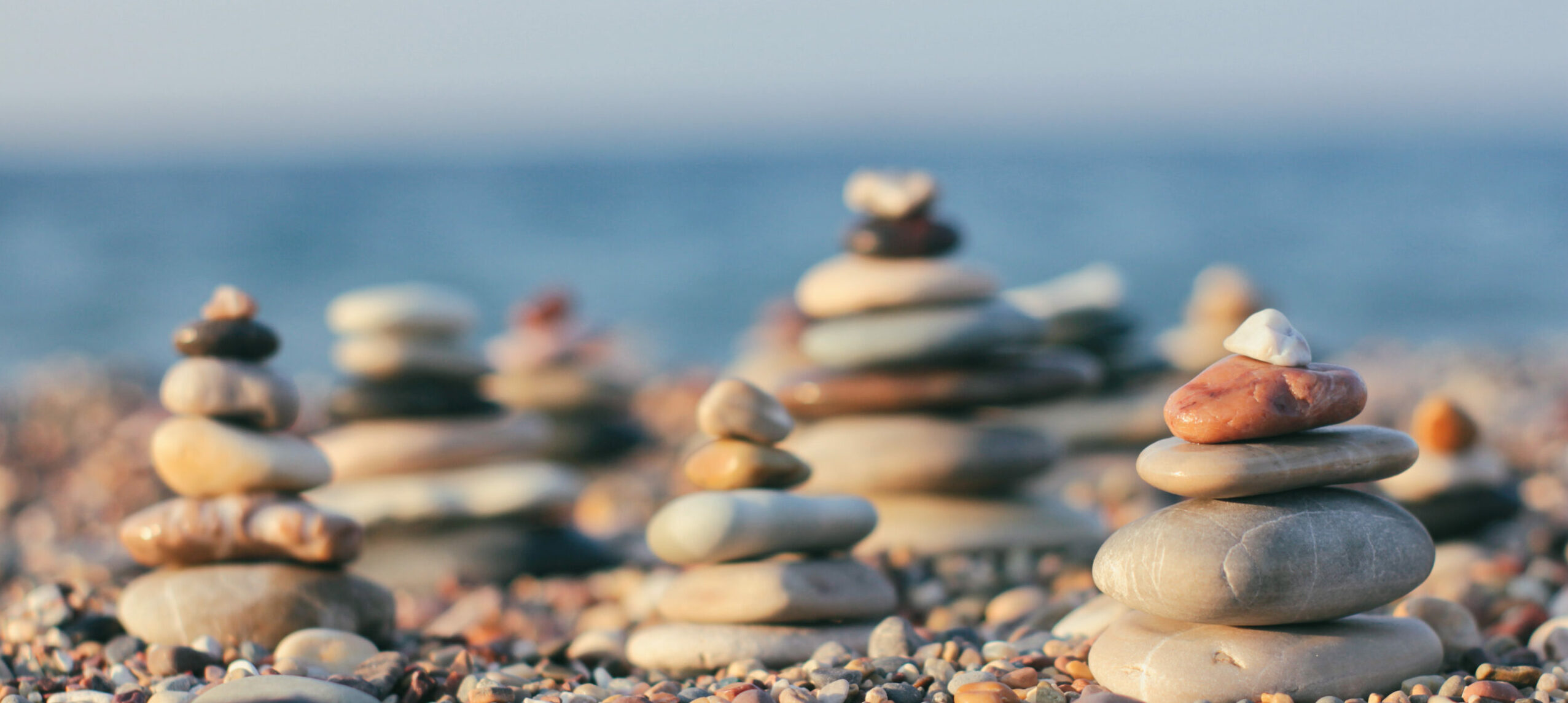 Zen pyramid of spa stones on the blurred sea background. Sand on